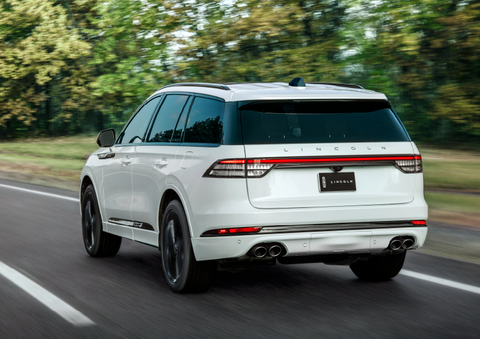 A white 2025 Lincoln Aviator® SUV is being driven away down a road lined with colorful trees. | Joe Rizza Lincoln of Orland Park in Orland Park IL