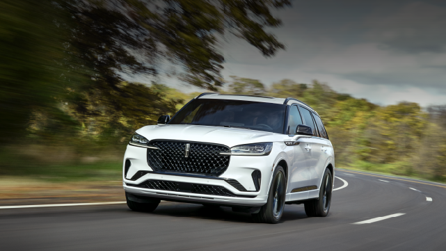 A white 2025 Lincoln Aviator® SUV is being driven down a road lined with trees. | Joe Rizza Lincoln of Orland Park in Orland Park IL