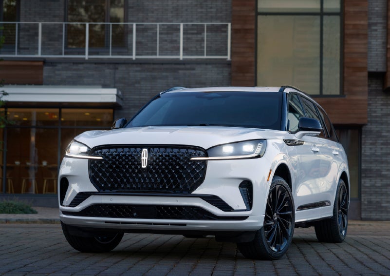 A 2026 Lincoln Aviator® Reserve model is shown with the available Jet Appearance Package parked near a restaurant. | Joe Rizza Lincoln of Orland Park in Orland Park IL