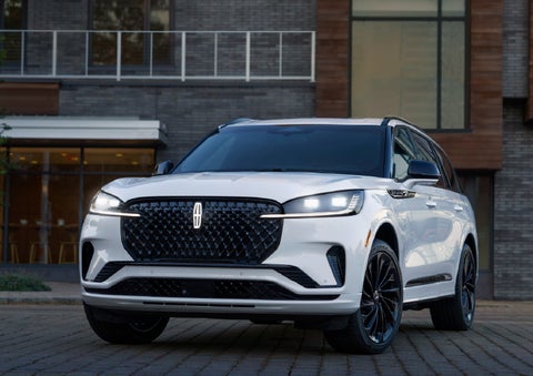 A 2026 Lincoln Aviator® Reserve model is shown with the available Jet Appearance Package parked near a restaurant. | Joe Rizza Lincoln of Orland Park in Orland Park IL