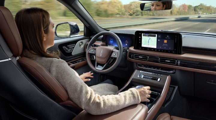 A 2026 Lincoln Aviator® SUV is being driven hands-free on a highway near a forest | Joe Rizza Lincoln of Orland Park in Orland Park IL