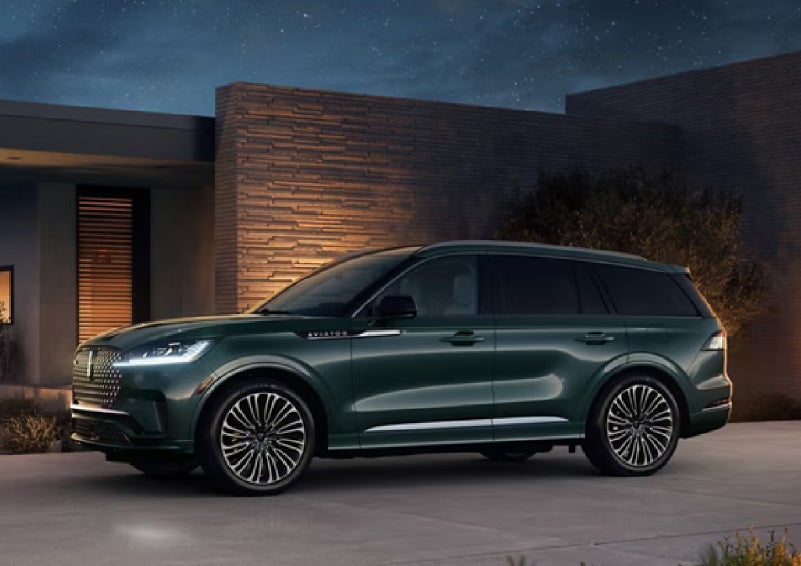 A green 2027 Lincoln Aviator® SUV is parked outside a contemporary home. | Joe Rizza Lincoln of Orland Park in Orland Park IL