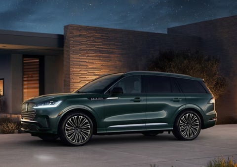 A green 2027 Lincoln Aviator® SUV is parked outside a contemporary home. | Joe Rizza Lincoln of Orland Park in Orland Park IL