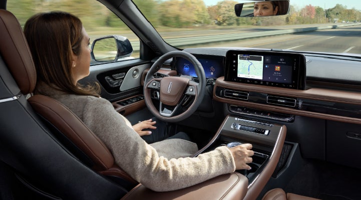 A 2027 Lincoln Aviator® SUV is being driven hands-free on a highway lined with trees. | Joe Rizza Lincoln of Orland Park in Orland Park IL