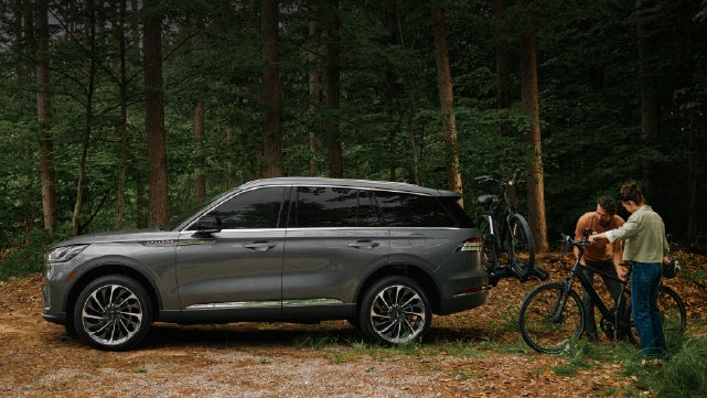 A father and son load e-bikes on a bike rack attached to a 2027 Lincoln Aviator® SUV. | Joe Rizza Lincoln of Orland Park in Orland Park IL